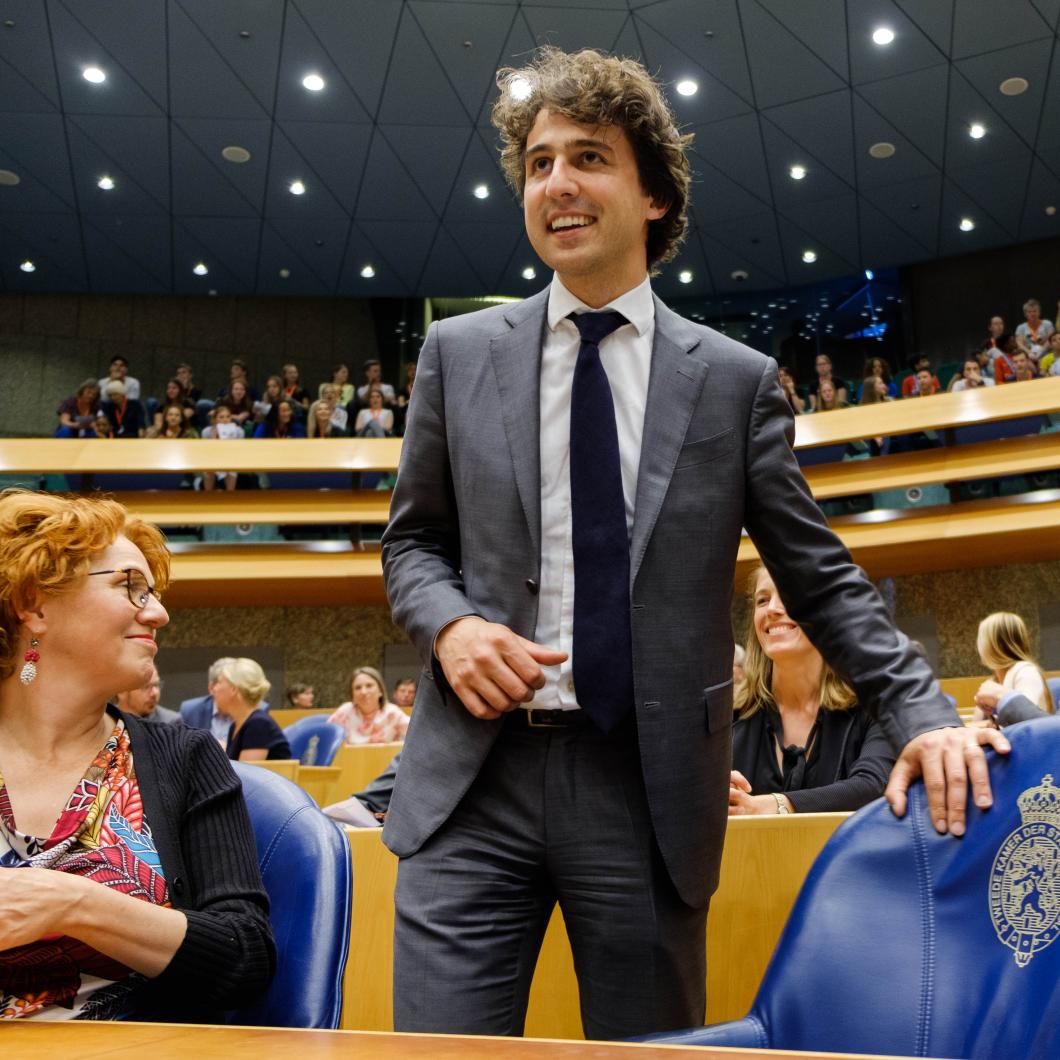 Jesse Klaver staat met een glimlach bij zijn stoel in de Tweede Kamer