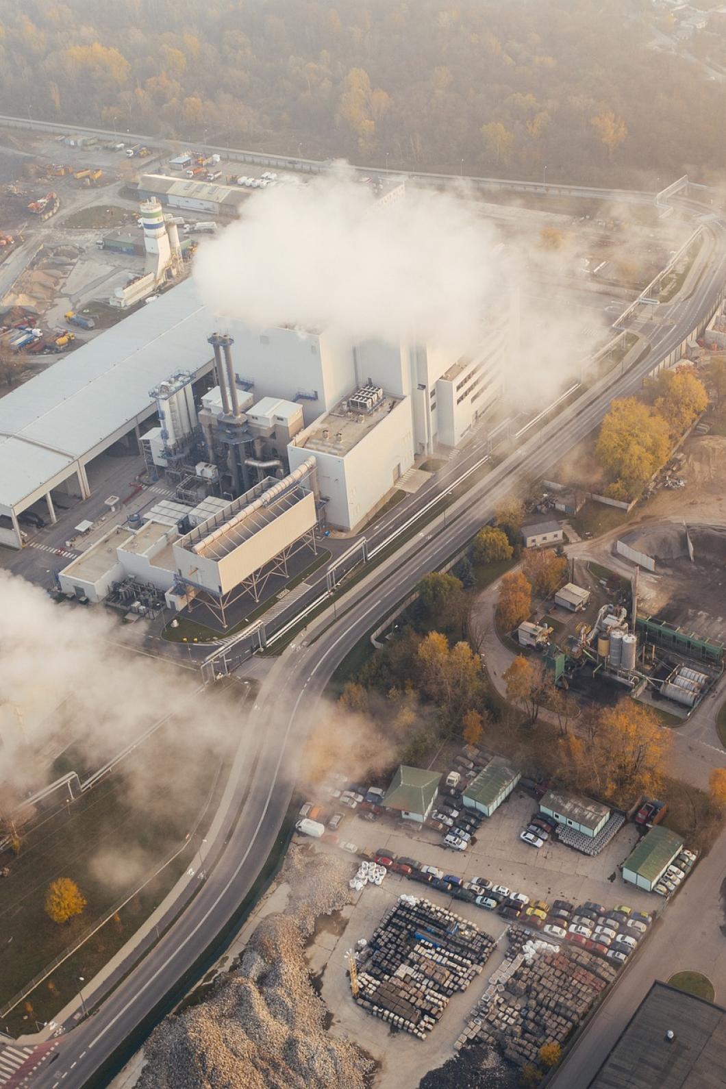 Een fabriek stoot grote witte rookpluimen uit