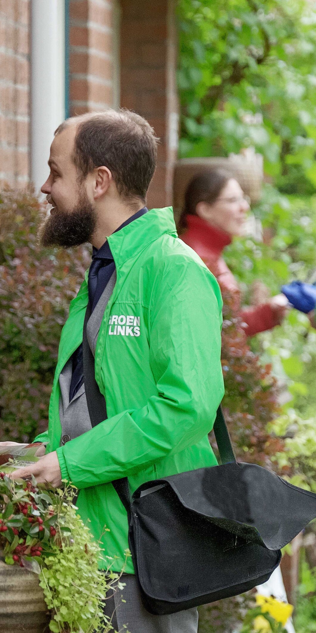 Enthousiaste vrijwilligers in een GroenLinks-jas bellen aan in de buurt om met de bewoners te spreken over wat zij willen dat de politiek voor ze doet.