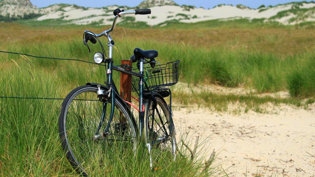 Een fiets staat geparkeerd in de duinen