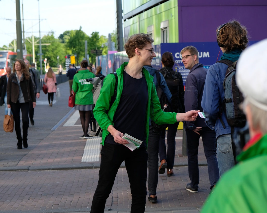 Een GroenLinks-vrijwilliger deelt flyers uit