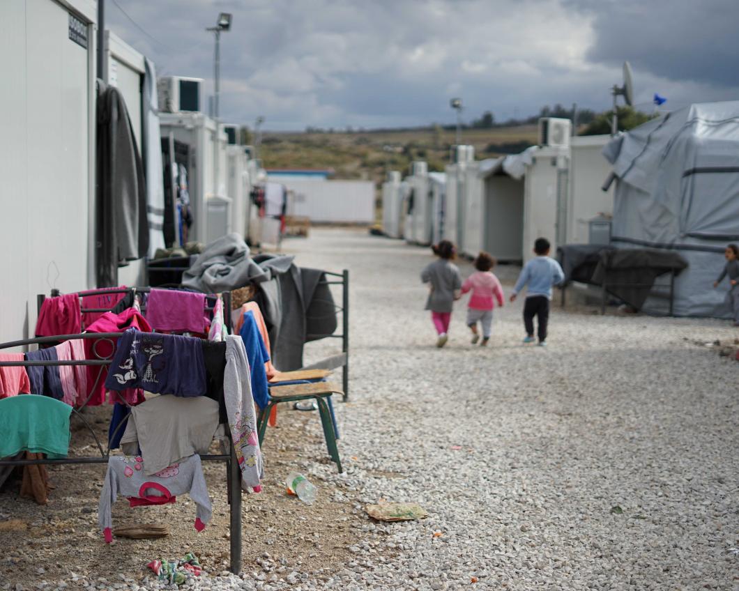Kinderen lopen langs wasrekken in een vluchtelingenkamp in Griekenland