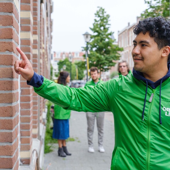 Een campagnevrijwilliger belt in een GroenLinksjasje aan bij een huis.