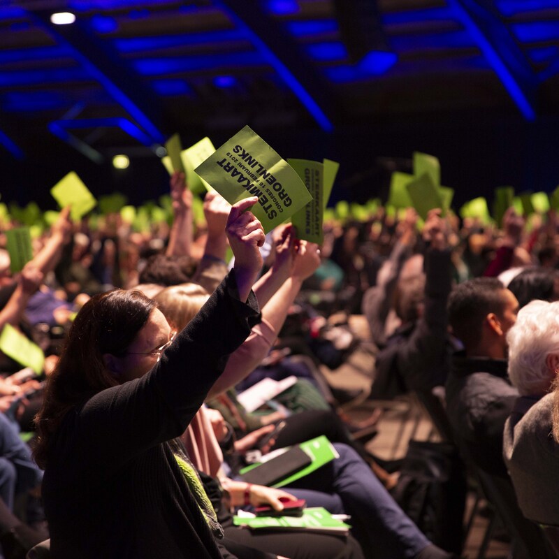Leden houden op het congres de groene stemkaart omhoog om hun stem uit te brengen op een ingediende motie.