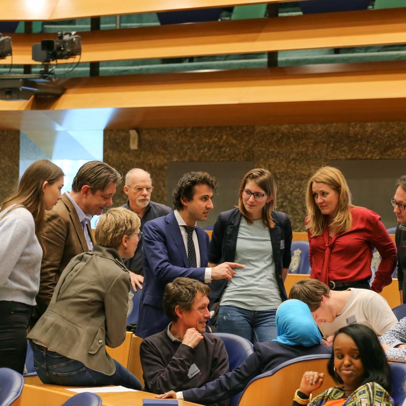 Jesse Klaver in de Tweede Kamer omringd door een groep mensen die aan zijn lippen hangt