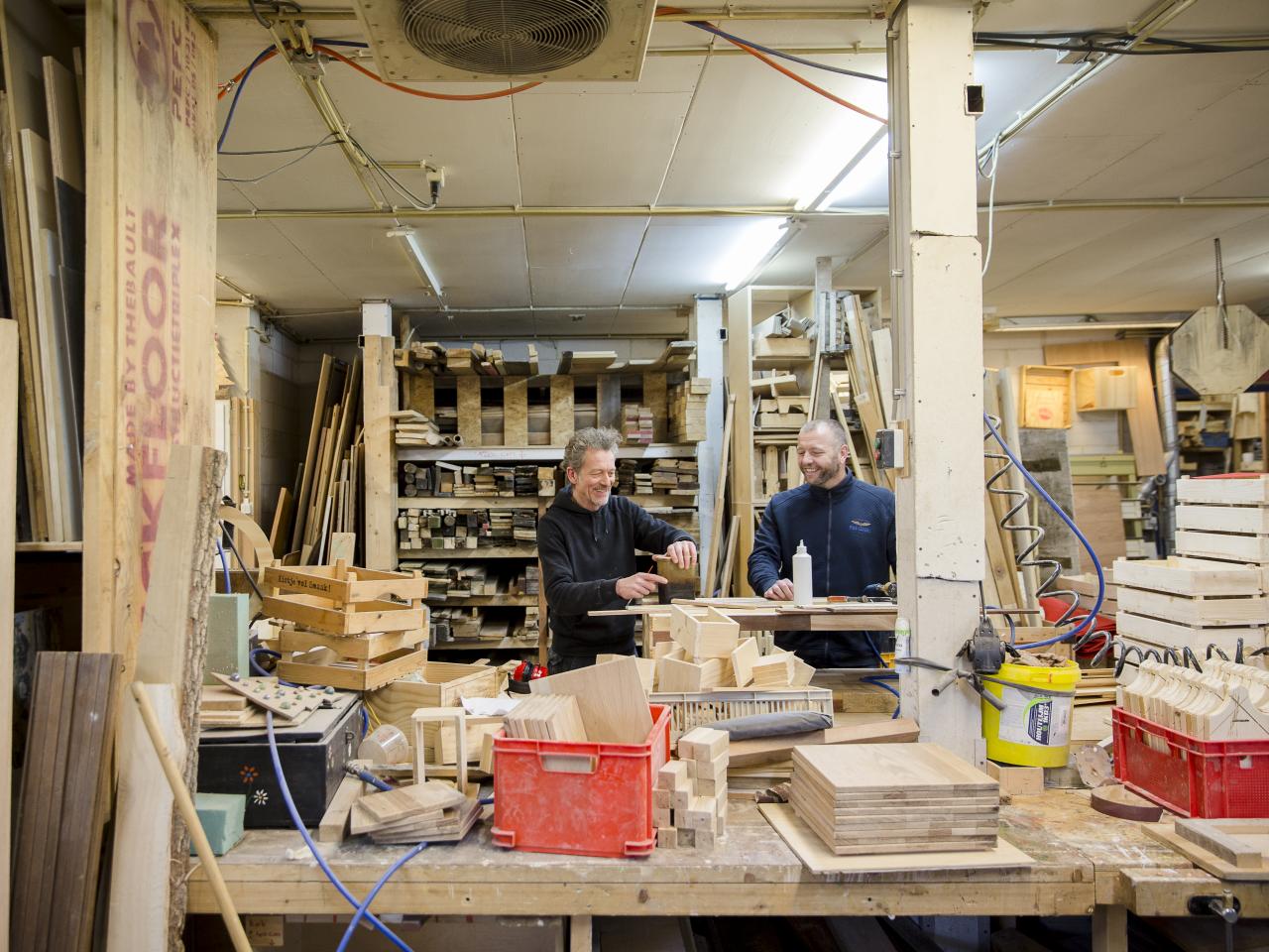 Twee timmermannen in hun atelier gevuld met verschillende soorten planken